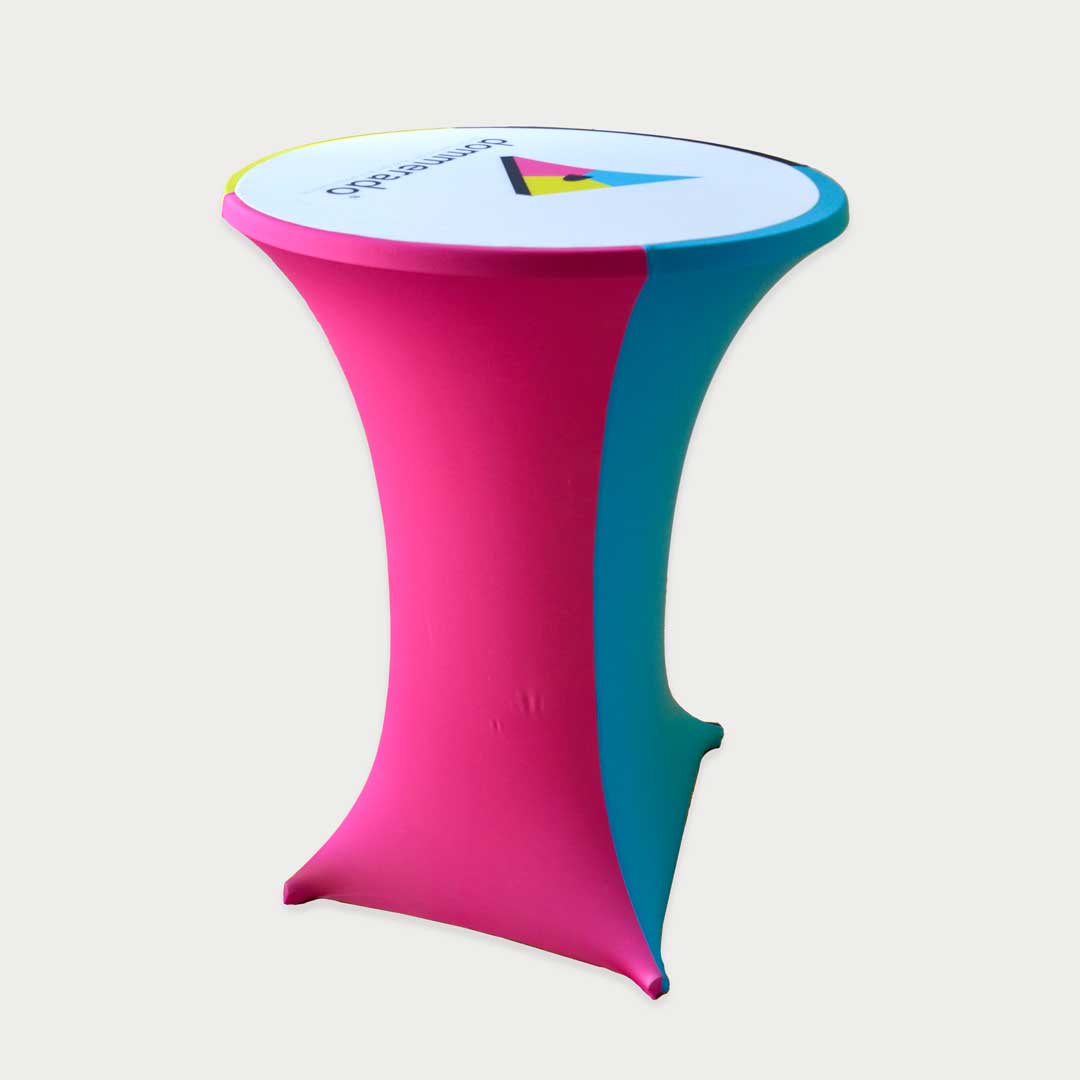 Runder Stehtisch mit bedrucktem Stretchüberzug in Magenta und Türkis sowie Logodruck auf der Tischplatte.